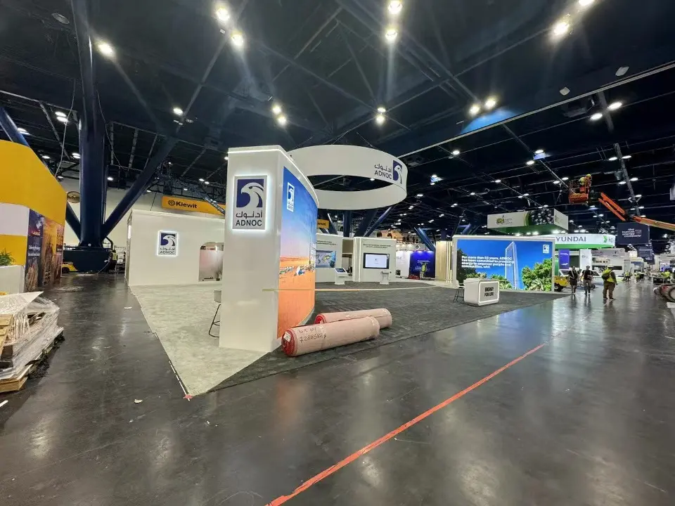 Long side of the booth with backlit graphics and carpet rolls nearby