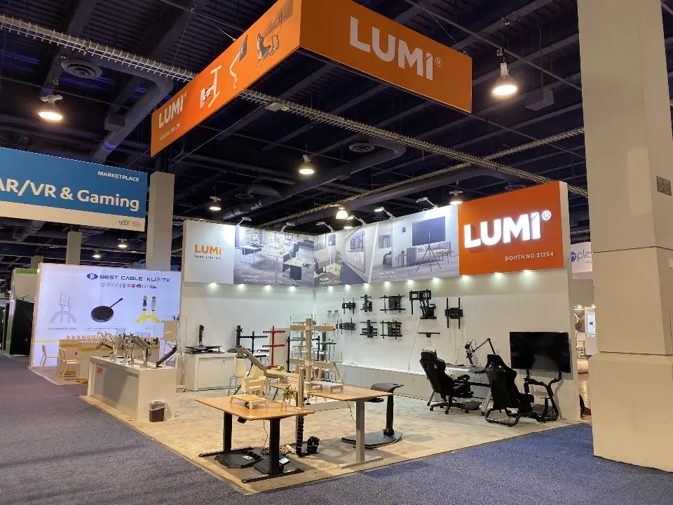Finished LUMI booth with desks, chairs and monitor mounts under the orange header