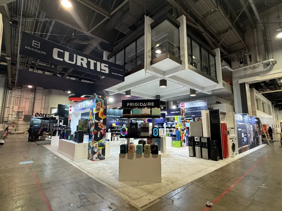 Booth corner with the hanging CURTIS sign and a Frigidaire mini fridge tower
