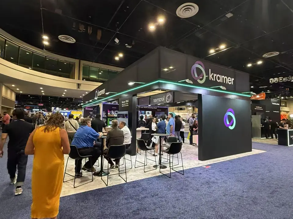 Wide view of the booth with Kramer logo box and busy seating area