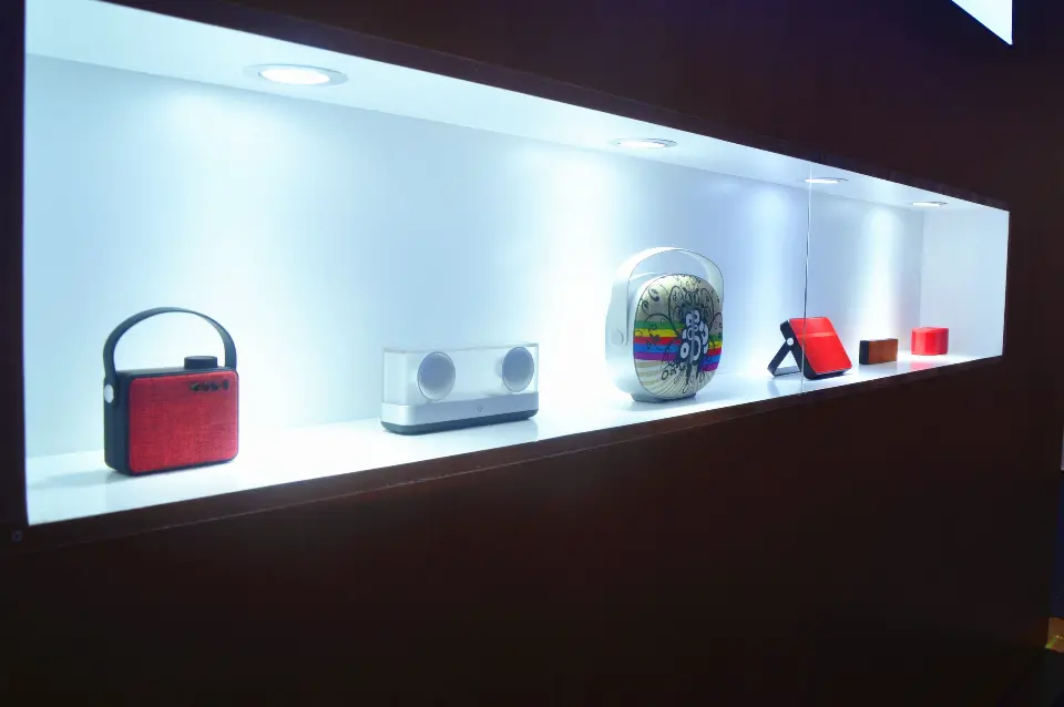 Lit display niche with portable speakers on a white shelf