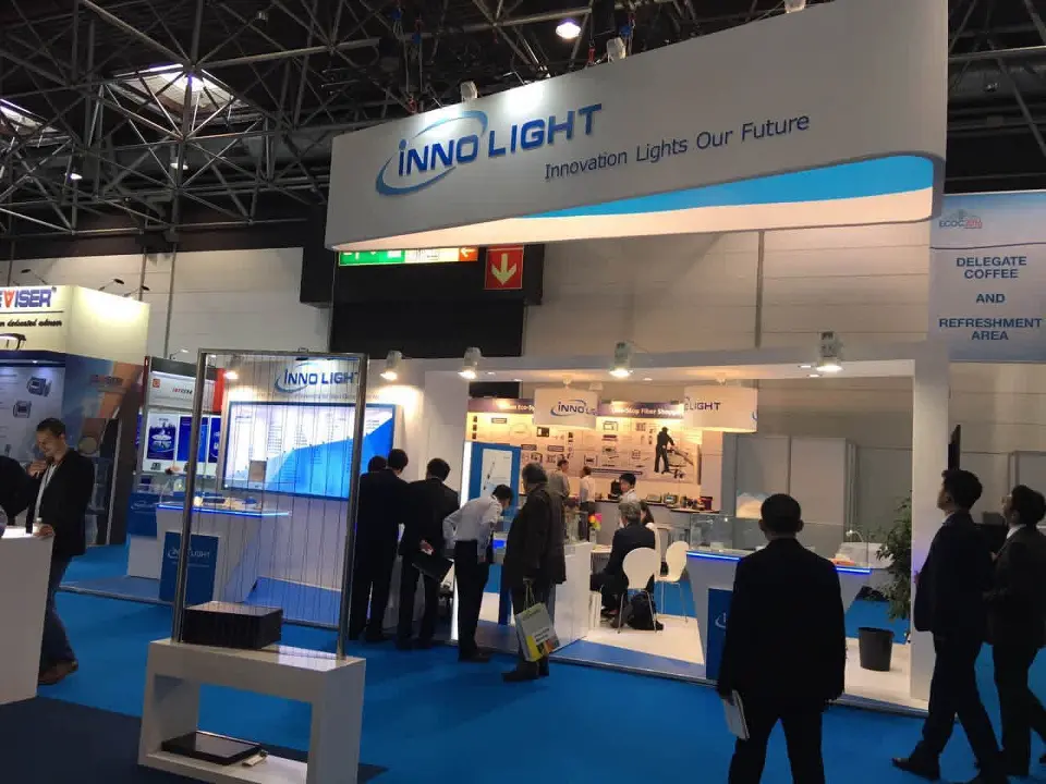 InnoLight booth with curved blue and white header and visitors at counters