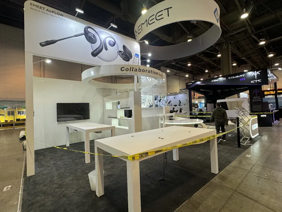 White demo table with conferencing devices under a large headset graphic