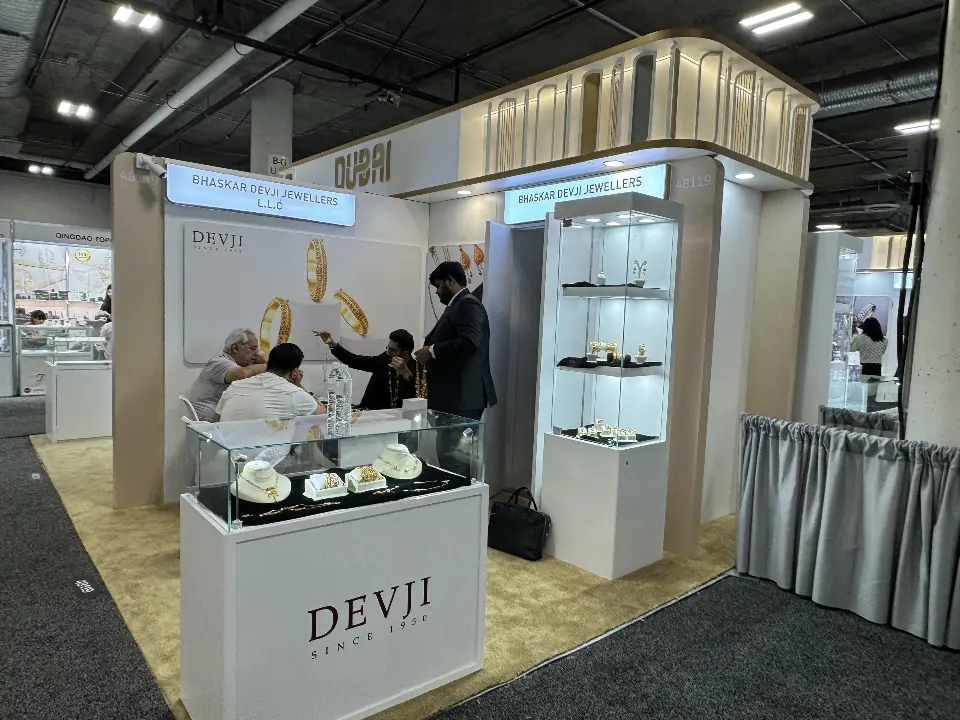 DEVJI showcase counter with jewelry beside a lit graphic wall