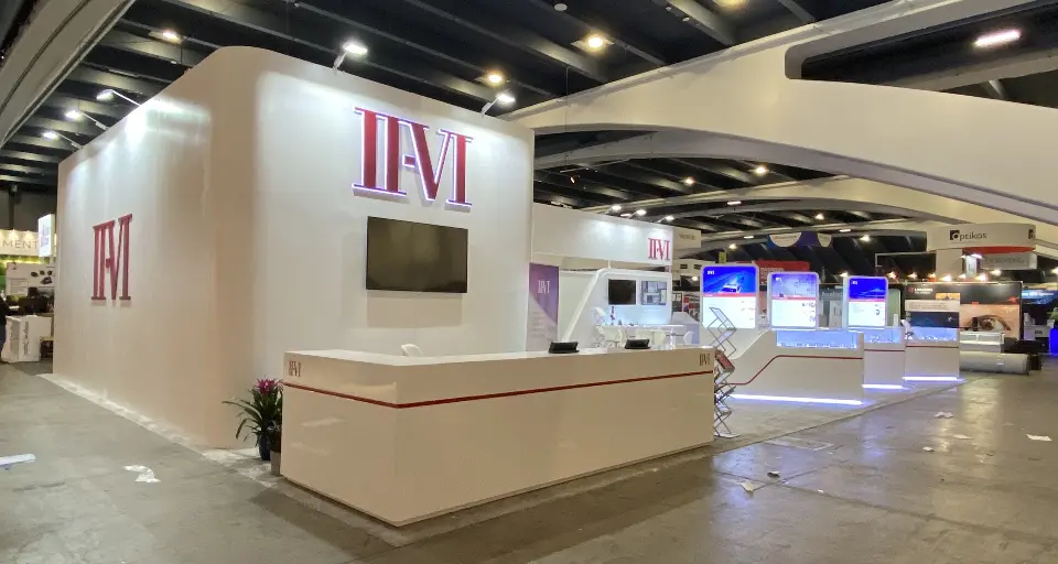White II-VI reception counter with red stripe under a sweeping white canopy