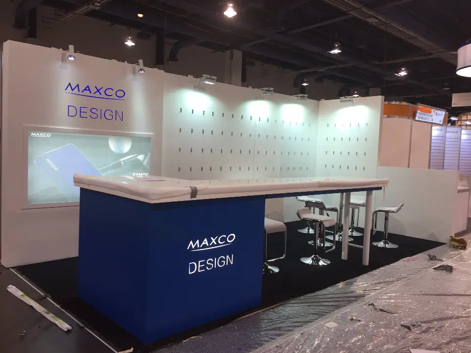 During build-up: white pegboard walls, blue MAXCO DESIGN counter and white bar stools