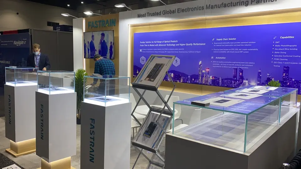 Glass product cases on white Fastrain pedestals and a glass-topped display table in front of the graphic wall