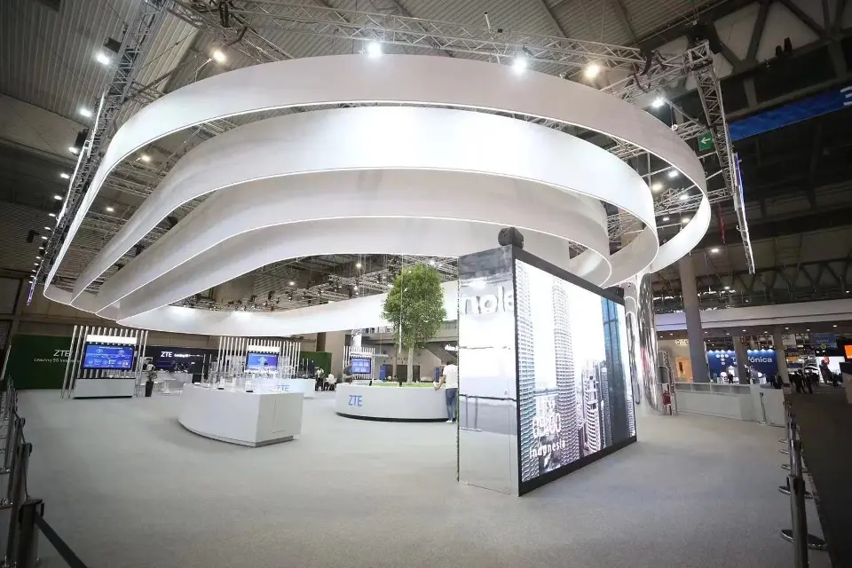 Open floor beneath the white ring canopy with central tree and vertical display screens