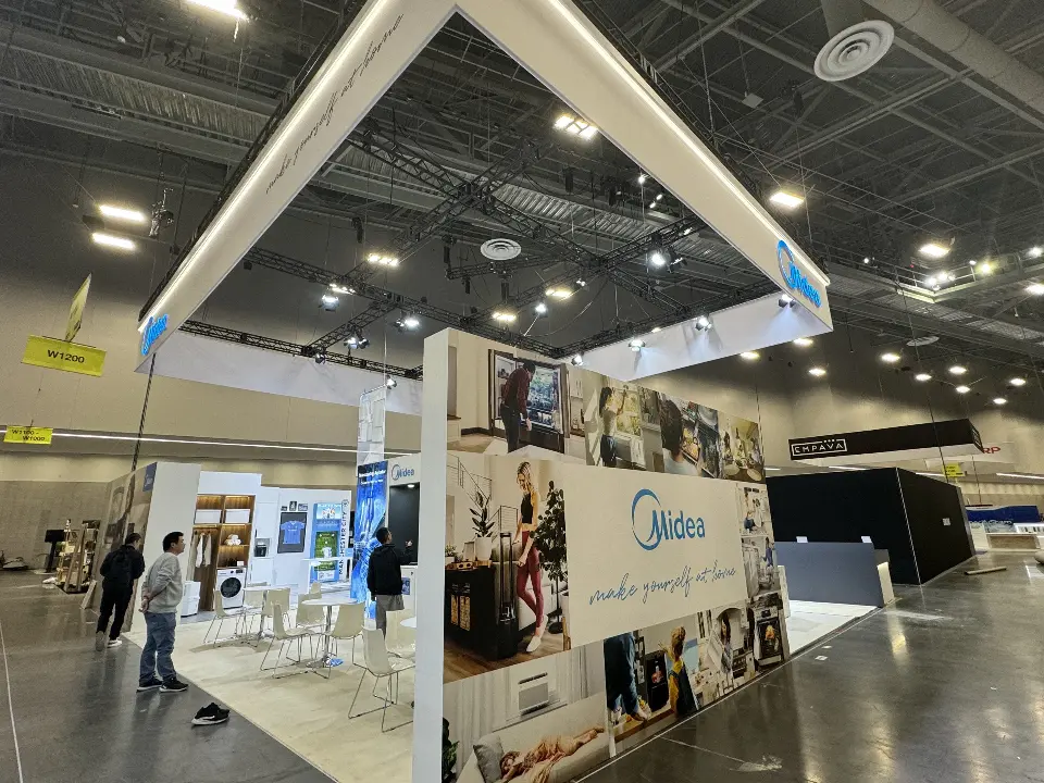 Booth corner with lifestyle graphics, an appliance wall and visitors walking past