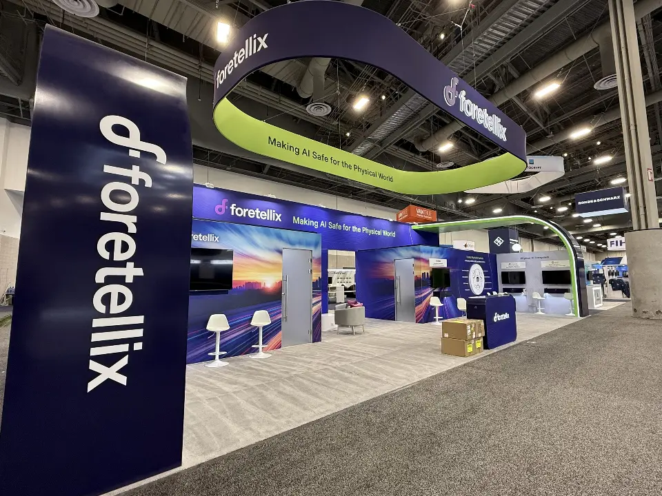 Logo column in the foreground with the ring and booth behind, landscape