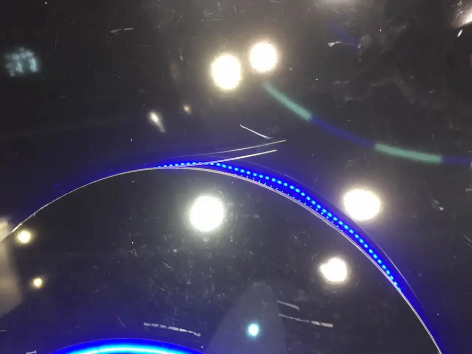 Ceiling spotlights reflected in the glossy black surface with a blue lit curve