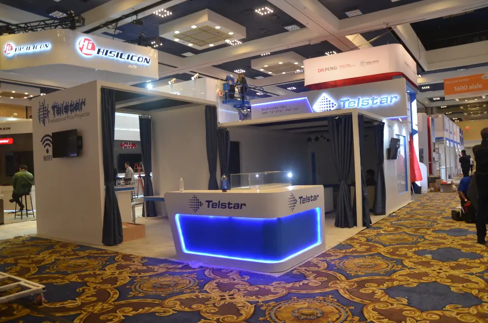 Side view of the Telstar stand during setup, with backlit logo fascia and booth number 1601