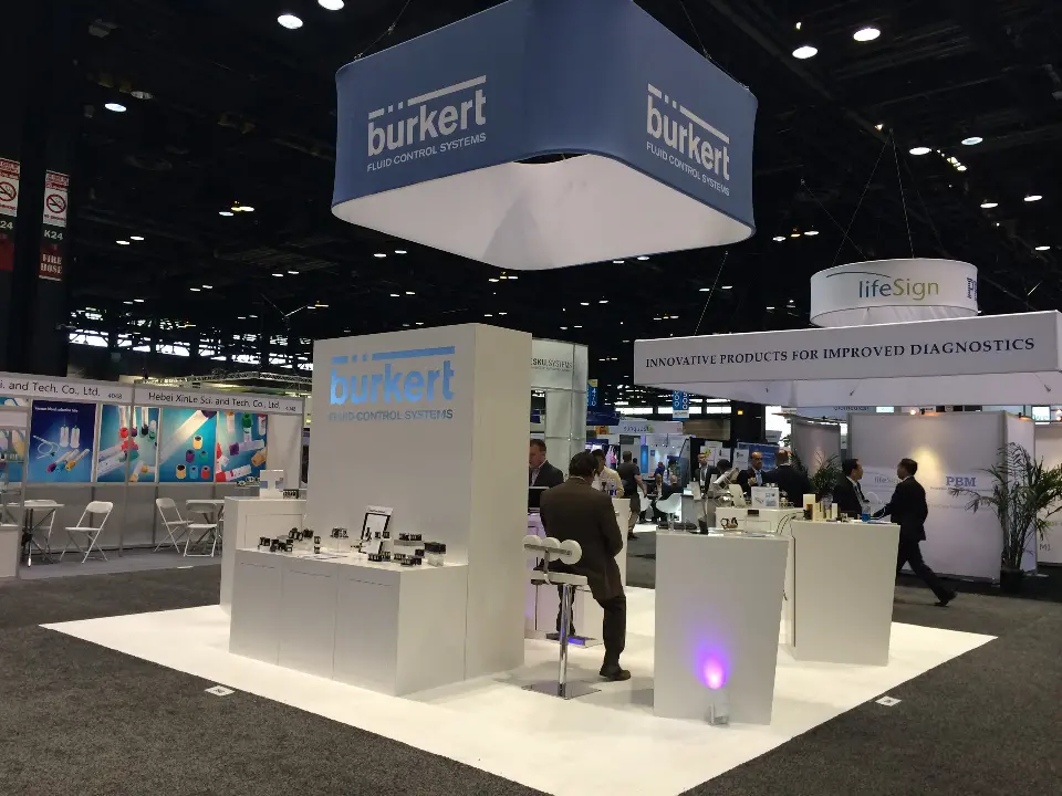 Closer view of burkert white plinths with product samples and a purple-lit base