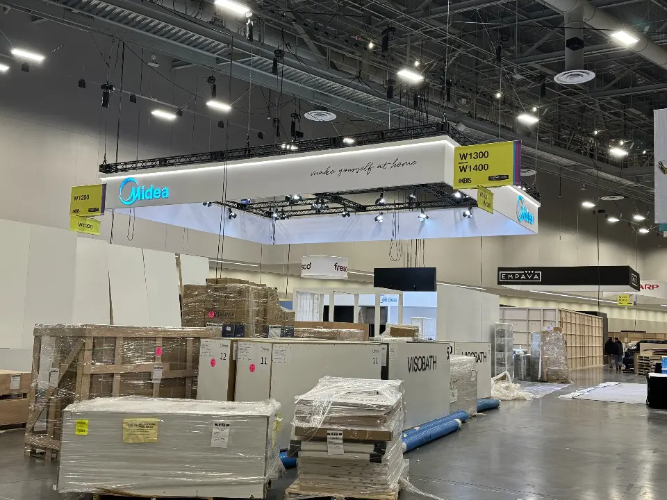 During installation: wooden crates in front of white display walls on the show floor
