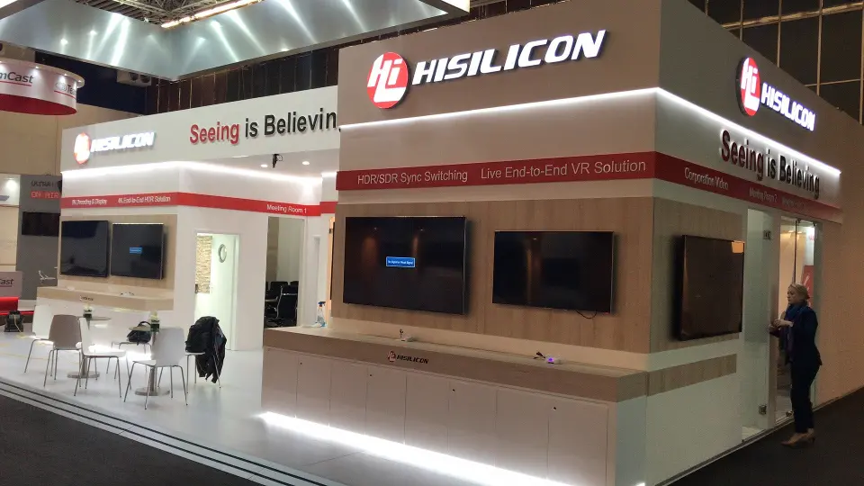 Long side of the booth with caf&eacute; tables and wood-look screen wall