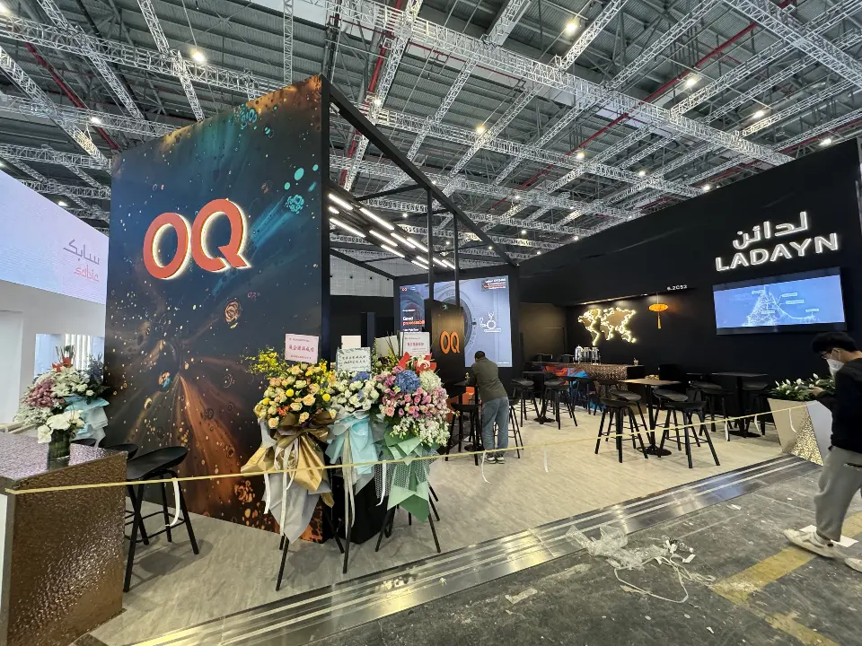 Welcome counter and flower stands at the base of the printed OQ tower