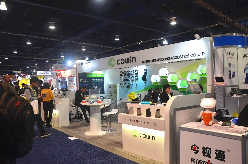Busy Cowin booth corner with lit logo counter and product displays