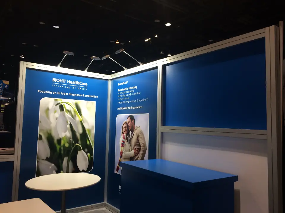 Blue modular panel booth with ROHIT HealthCare product graphics, round white table and blue counter