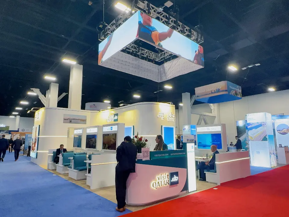 Overview of the Qatar stand with truss hanging sign and pink logo counter
