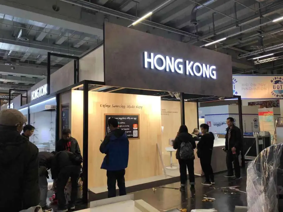 Wood-look pavilion header with HONG KONG lettering above an information desk and visitors