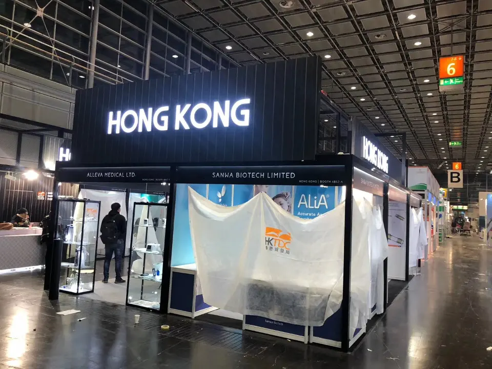 Black HONG KONG fascia over a row of booths in white covers, one stand open