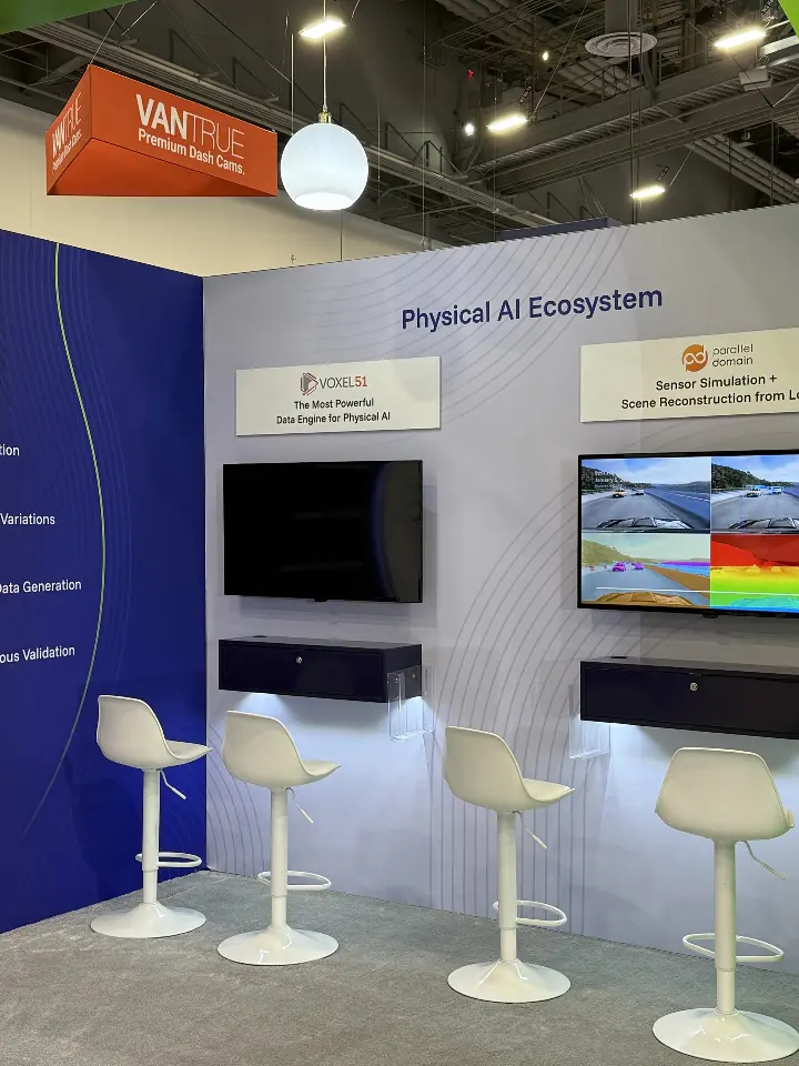 Physical AI Ecosystem demo wall with two screens and white bar stools