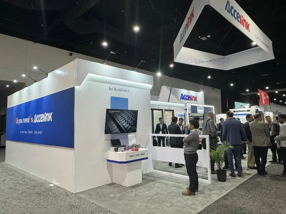 Side view of the white Accelink booth with blue graphic wall and crowd