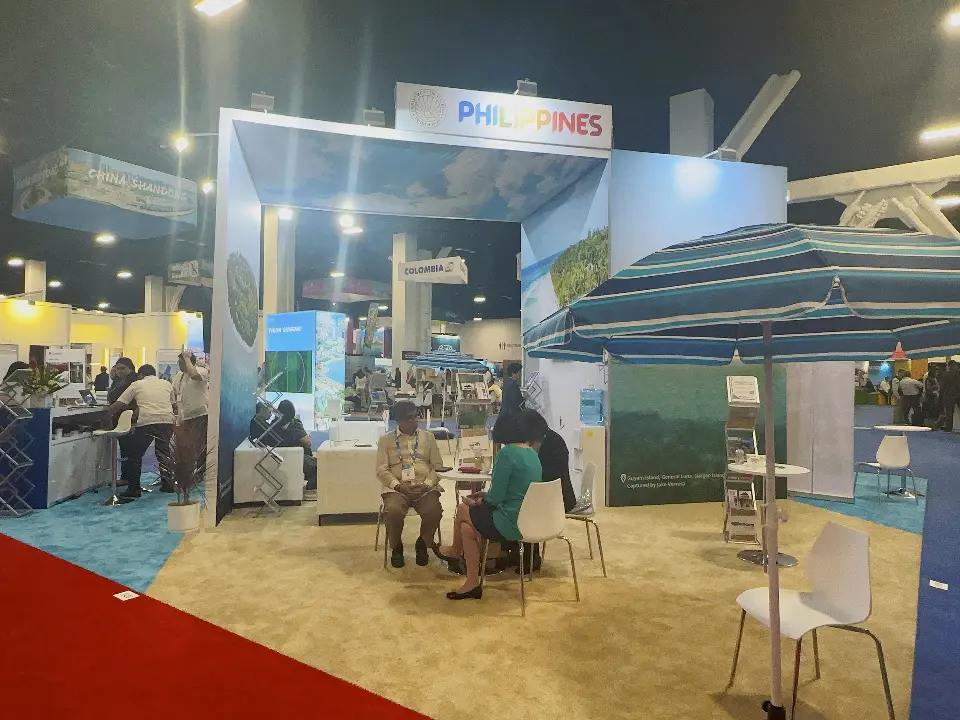 Philippines open portal frame with rainbow PHILIPPINES header, sand-coloured carpet and visitors meeting at tables