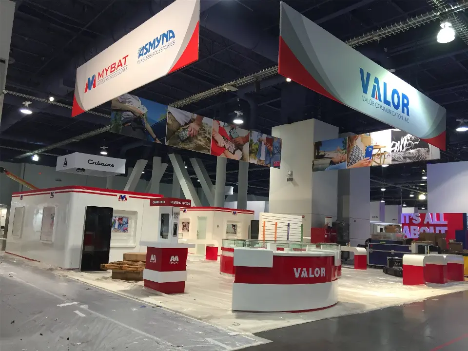 During installation: wide aisle view with all three hanging banners over the booth