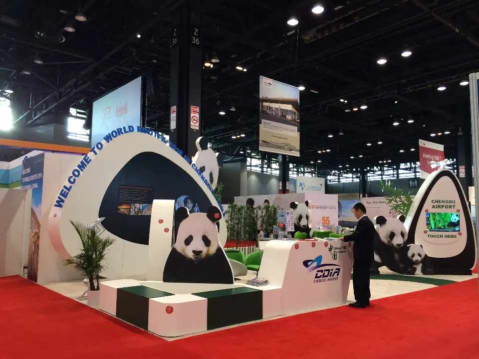Front of the Chengdu Airport booth with panda arch, seating and green chairs on red carpet