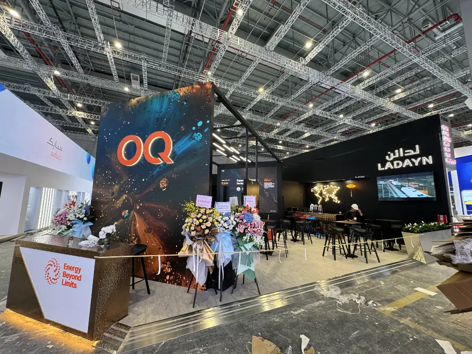 OQ tower and logo counter in front of the black booth frame and lounge seating