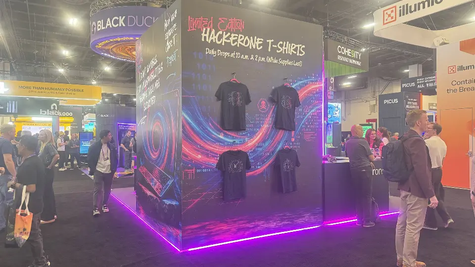Limited Edition HackerOne T-shirts wall with swirling graphic and visitors nearby