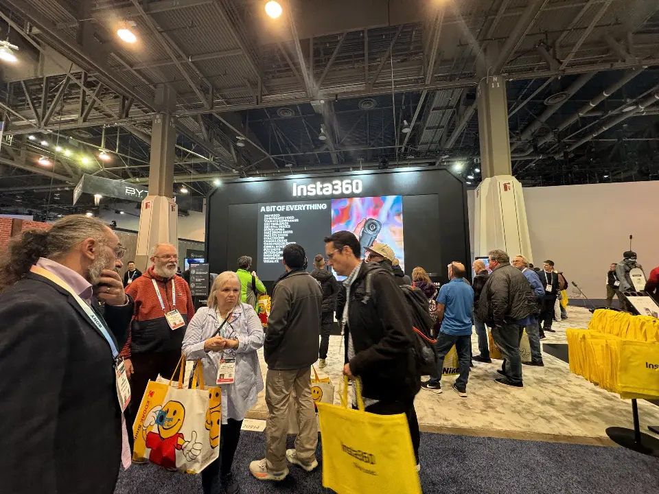 Visitors with yellow tote bags crowding the booth front