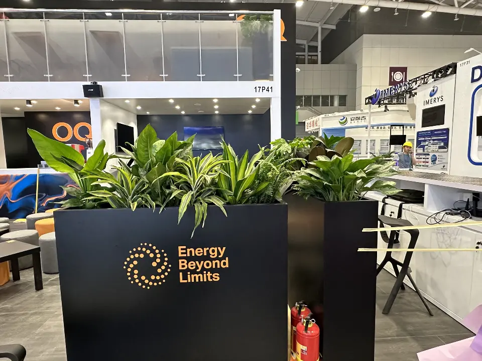 Black planter with Energy Beyond Limits logo and plants at the booth edge