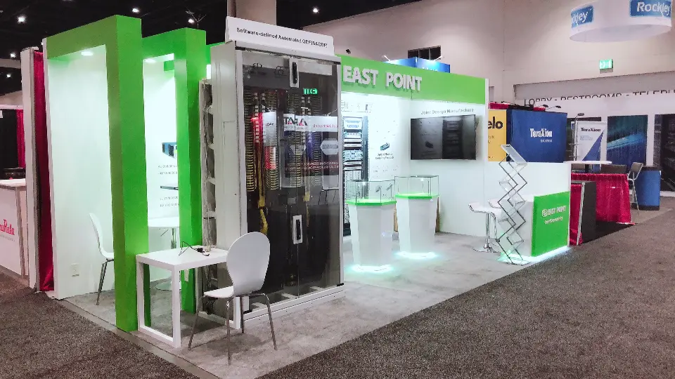 Angled view of East Point booth with green header, server racks and white table