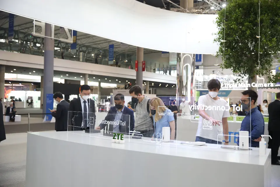 Guests testing phones along a white counter with green lawn edge