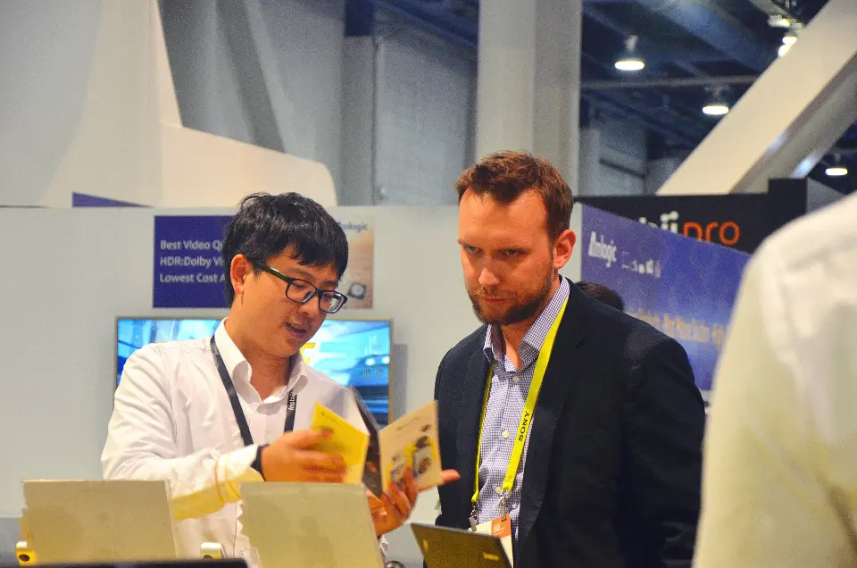 Staff showing a product card to a visitor at the Insta360 booth