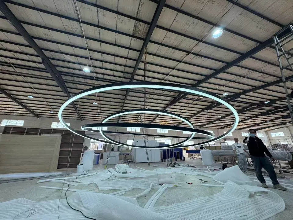 Large light rings test-hung in a workshop above white protective sheeting