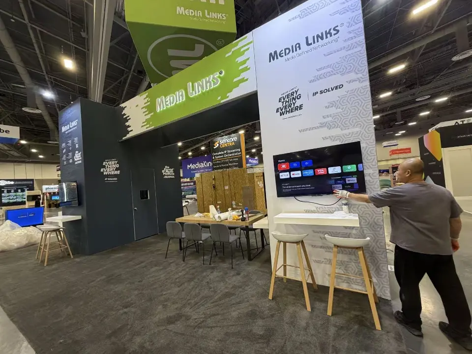 During build-up: Media Links green header, white column with video screen and wood-look stools
