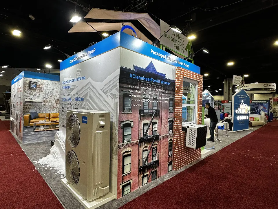 Corner of the Midea stand with a brick townhouse facade, window units and an outdoor heat pump