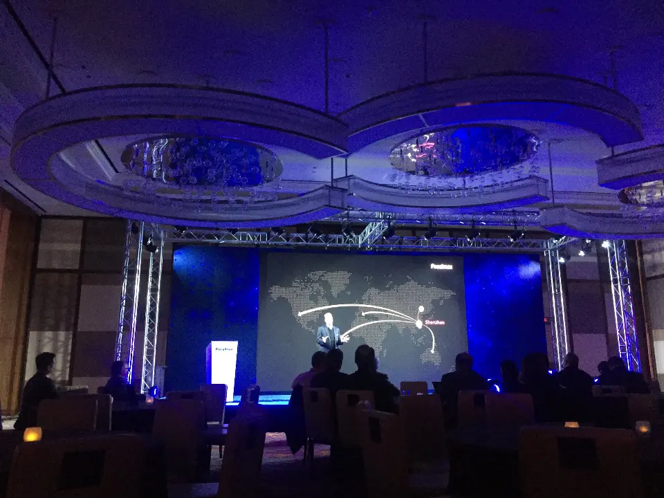 Stage screen showing a product outline graphic with the audience in silhouette