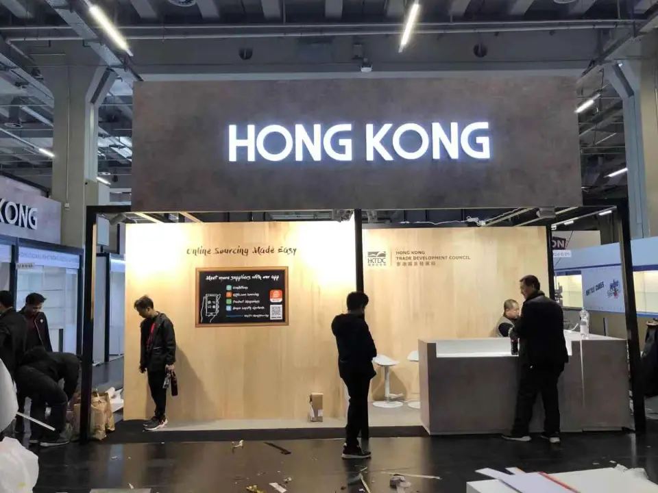Front information desk under a lit HONG KONG header with staff standing nearby