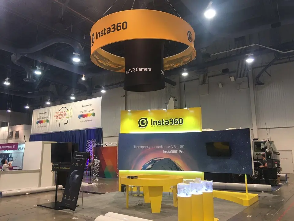 Front view of the Insta360 booth with yellow header, curved graphic wall and orange ring sign
