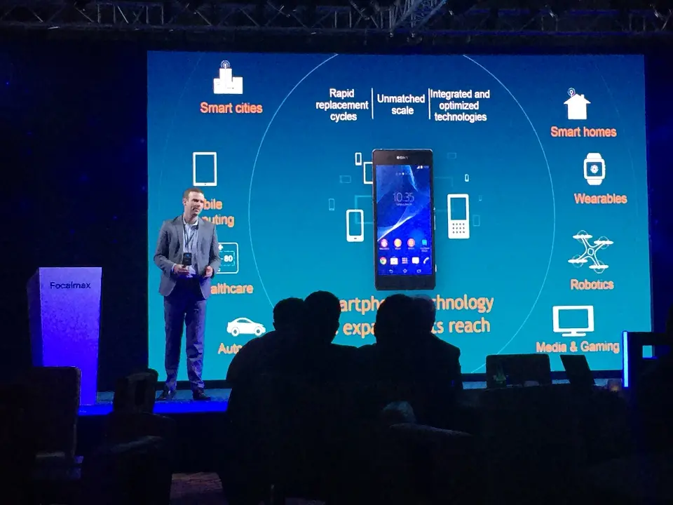 Speaker standing before a smart device diagram on the large stage screen