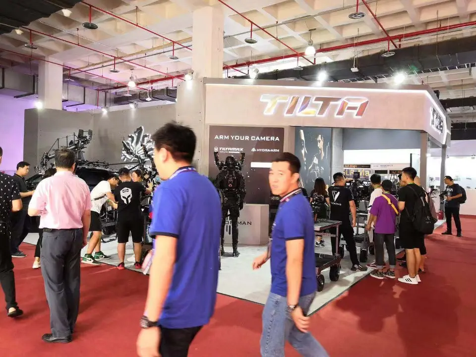 Visitors around the camera rigs along the open side of the booth