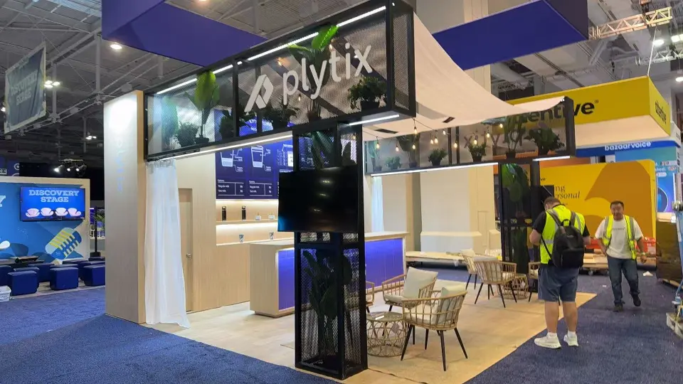 Front view of the Plytix coffee bar and wicker lounge under a mesh frame with plants