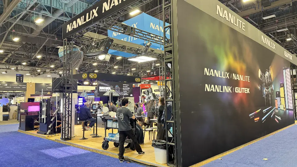Long dark NANLUX and NANLITE graphic wall beside an open truss demo area with lighting gear