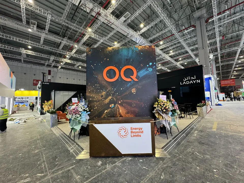 OQ tower with welcome counter and flower stands seen from the aisle at an angle