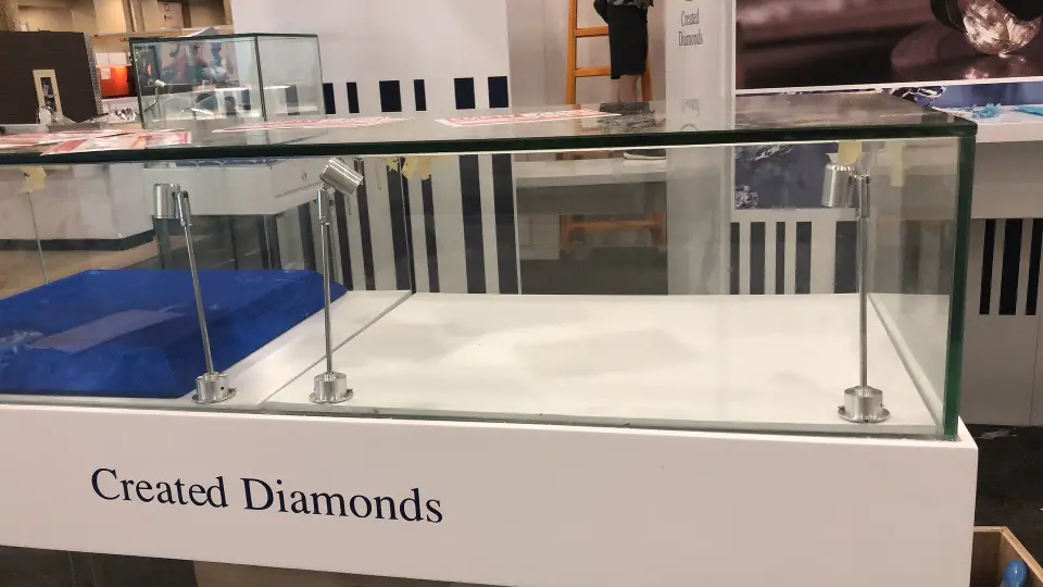 Side angle of an empty glass showcase on a white Created Diamonds pedestal