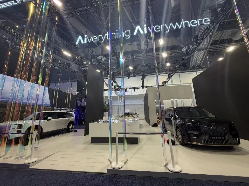 Two dark cars under Aiverything Aiverywhere lettering on a black wall